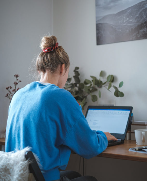 Astronauta de la NASA da consejos para pasar la cuarentena; mujer con sudadera azul y chongo haciendo home office, usando laptop