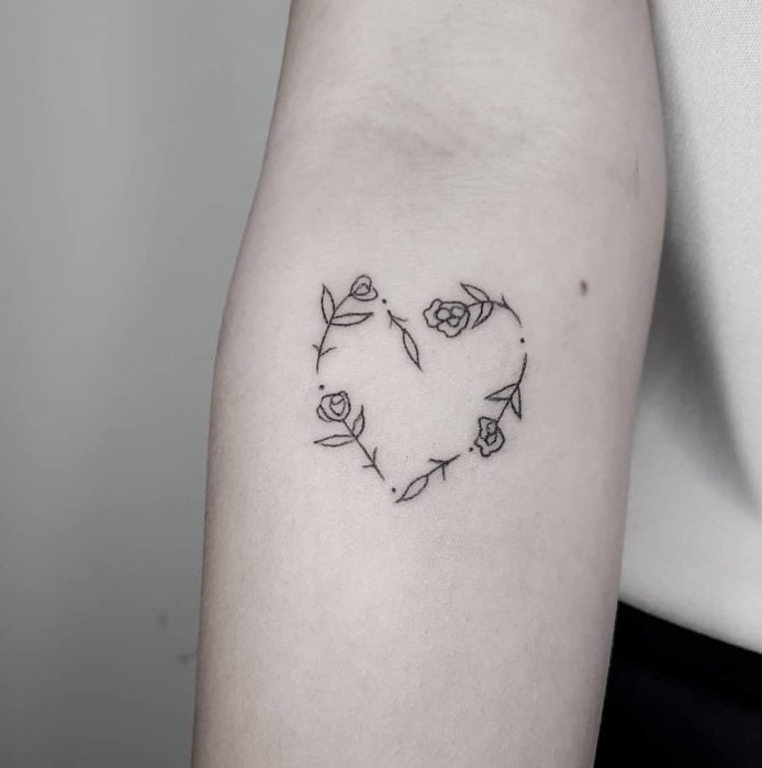 Tatuaje al estilo hand poke de un corazón hecho con rosas