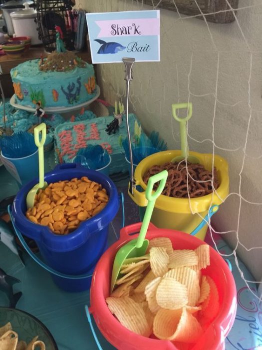 cubetas de plástico de colores con botanas para fiesta infantil