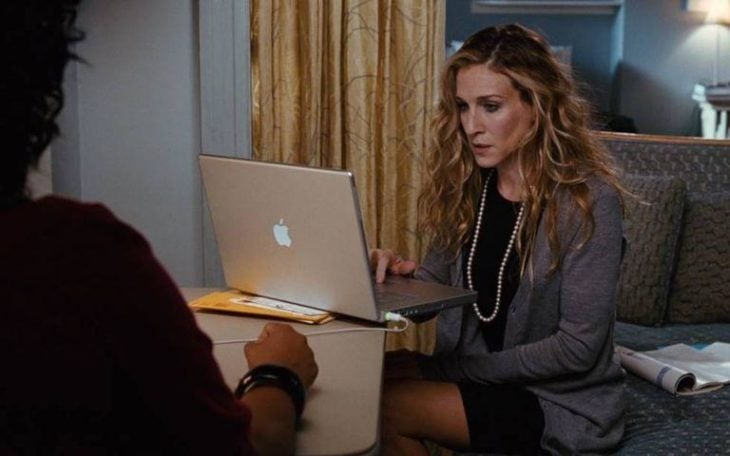 Carrie Bradshaw con saco formal escribiendo en su laptop mac