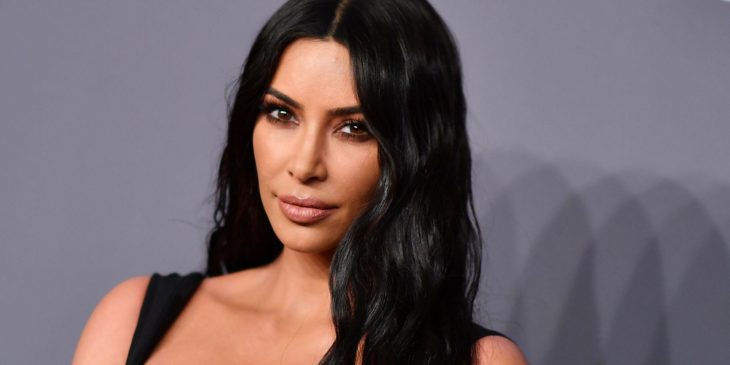 Kim Kardashian sonriendo ligeramente posando en una alfombra gris