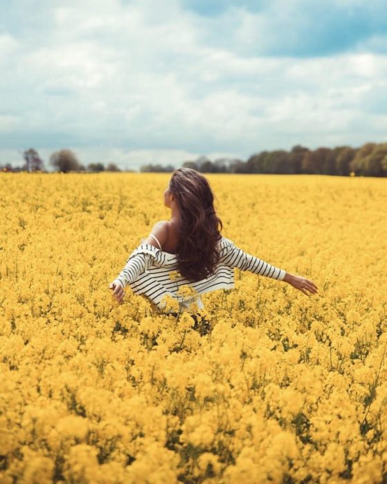 Mujer con los brazos extendidos en campo de flores