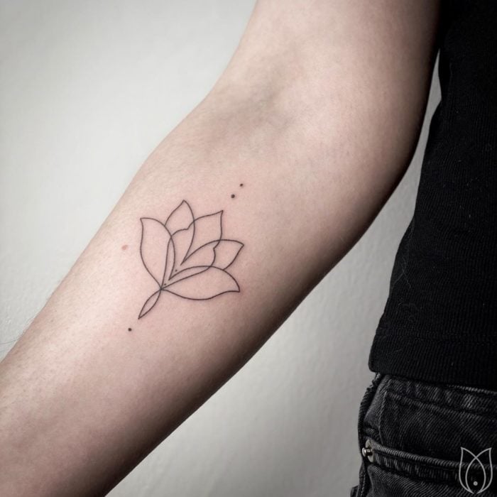 Tatuaje al estilo hand poke de la silueta de una flor de loto