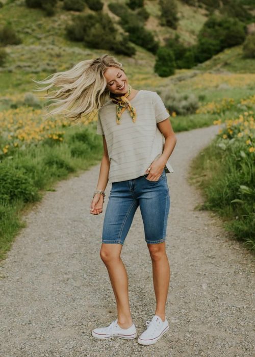 Chica usando bermudas de mezclilla con blusa de color café y una pañoleta atada al cuello 