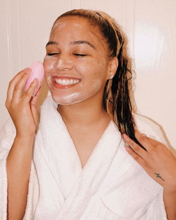 Chica limpiando su rostro con cepillo ultrasonico 