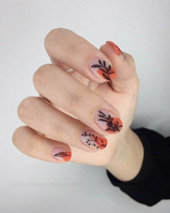 Manicura de estilo francés con flores en tonos negros con naranja