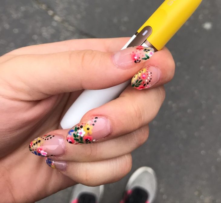 Manicura estilo francés con flores de colores amarillas, naranjas y rojas