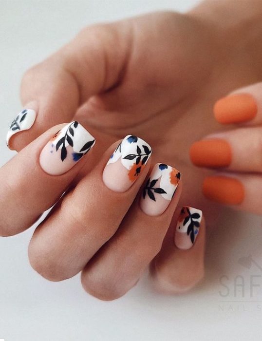 Manicura estilo francés con flores naranjas con fondo blanco y guias verdes 