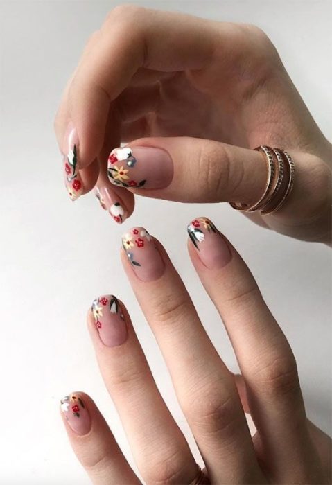 Manicura estilo francés con flores miniaturas en tonos amarillo, naranja y verde