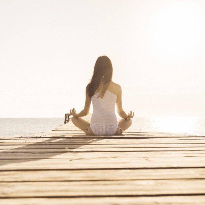 Chica meditando en un muelle