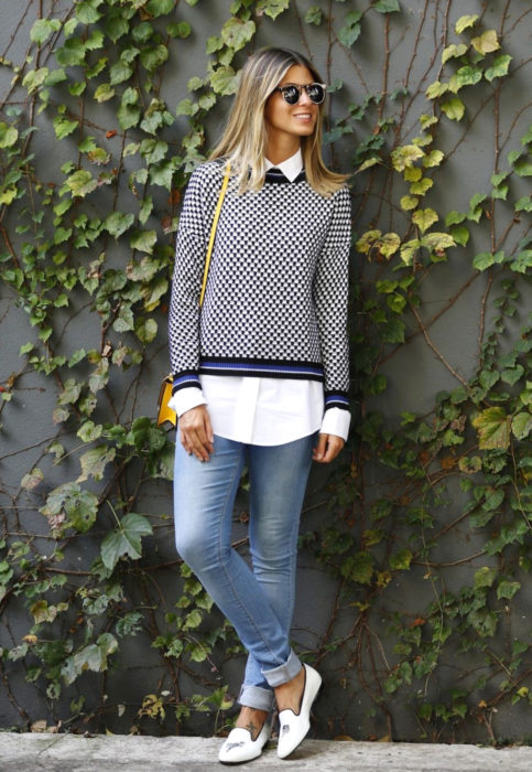 Outfit con blusa blanca; mujer rubia frente a enredadera con suéter y camisa debajo