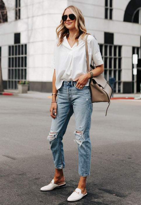 Outfit con blusa blanca; mujer rubia en la calle con mom jeans desgastados