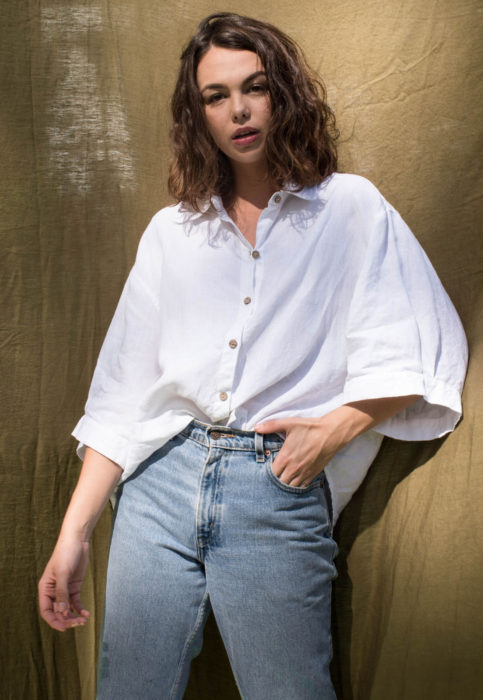 Outfit con blusa blanca; mujer castala de cabello corto y ondulado, camisa oversized