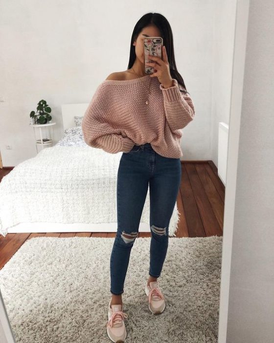 Chica morena de cabello largo toma selfue con jeans y suéter rosa palo 