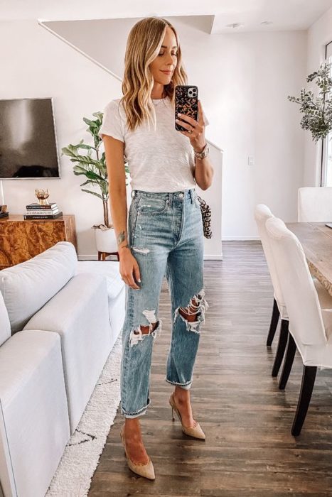 Mujer rubia toma selfie con jeans rotos y blusa blanca