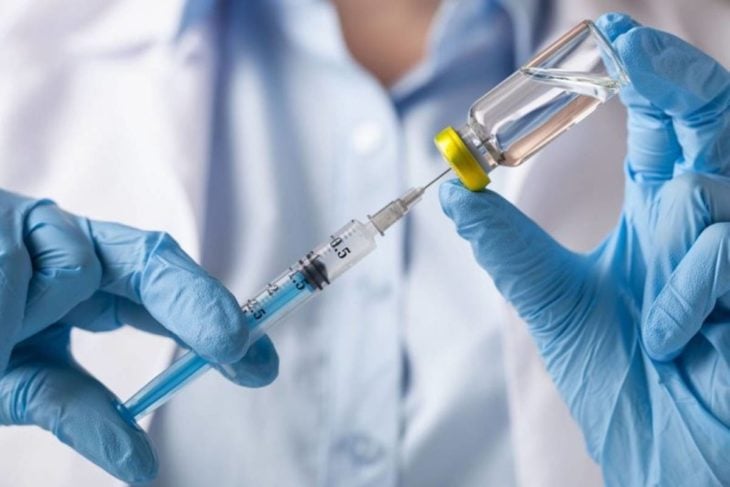 Doctor insertando vacuna en un frasco de medicina