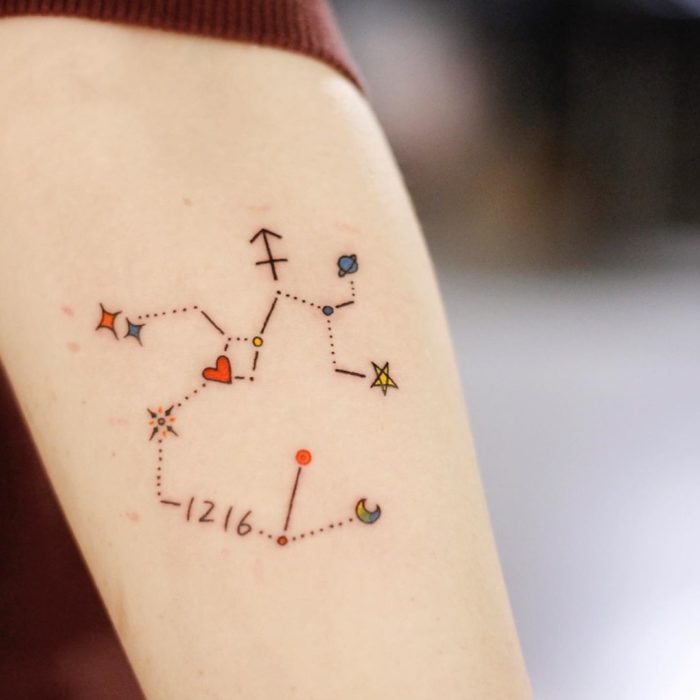 Tatuaje de la constelación de sagitario a color en el área del antebrazo