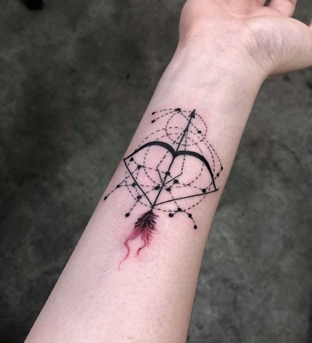 Tatuaje de el arco y la flecha del signo de sagitario en el área del antebrazo a tinta negra y de color