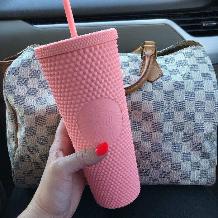 Chica sosteniendo un vaso rosa de starbuck 