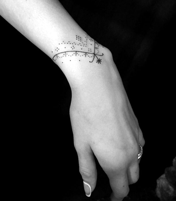 Tatuajes femeninos y discretos en las manos; brazalete de líneas y puntos
