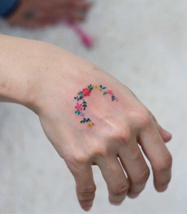 Tatuajes femeninos y discretos en las manos; corona de flores acuarela