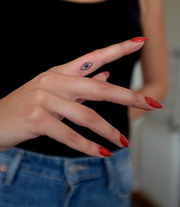 Tatuajes femeninos y discretos en las manos; ojo minimalista en el dedo