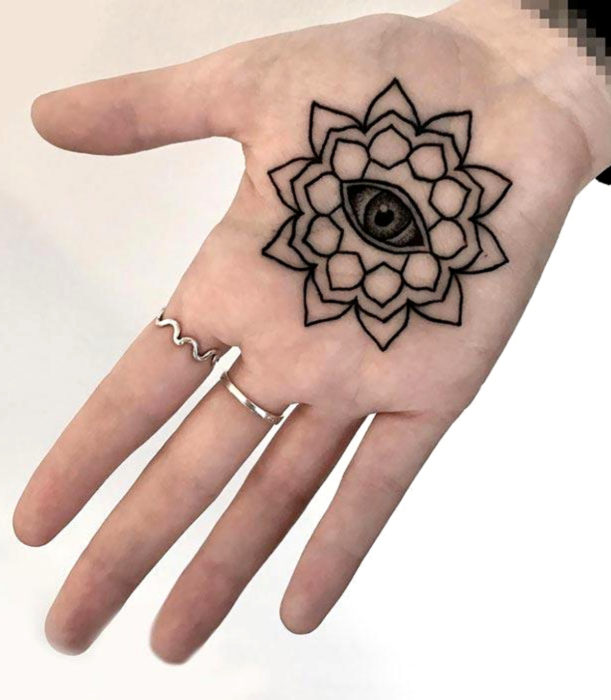 Tatuajes femeninos y discretos en las manos; flor de loto con ojo en la palma de la mano