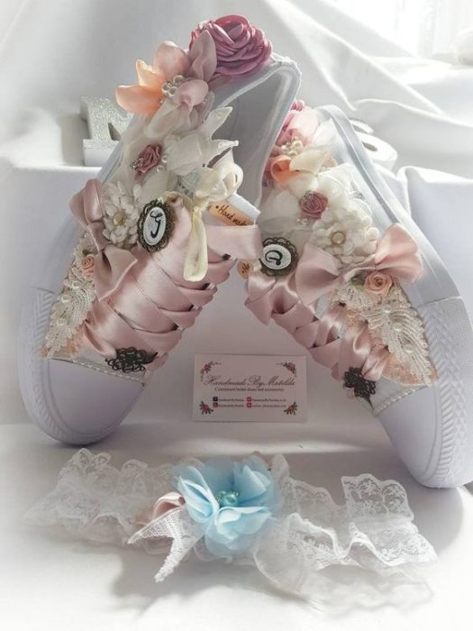 Tenis blancos con flores a lso costados y cintillas de listón rosa pastel para bodas