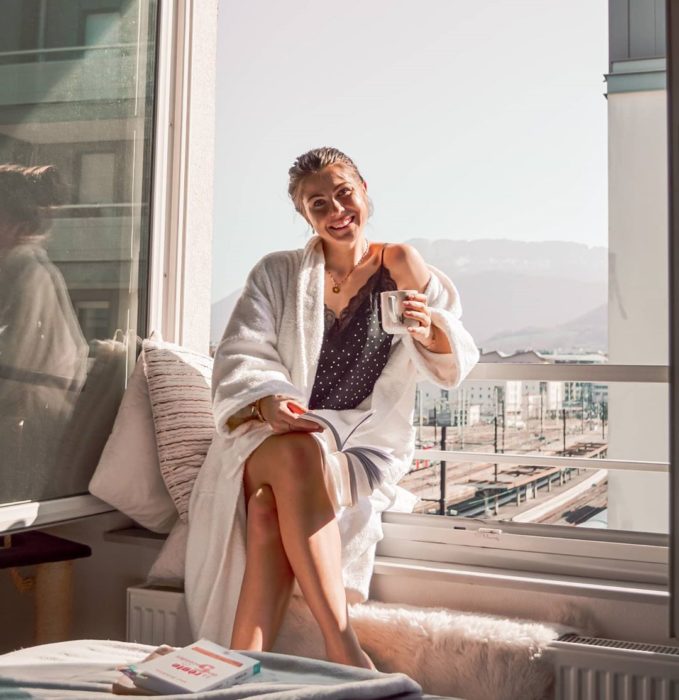 Chica tomando el sol desde su ventana