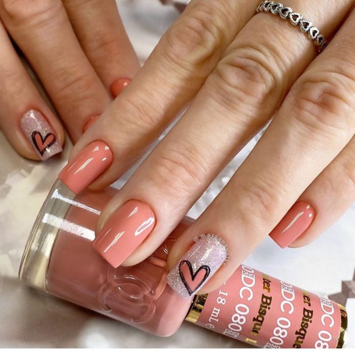 Manicura color salmon con dedo anular en brillo y decorado