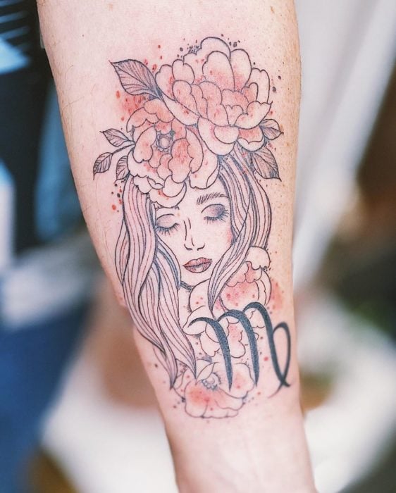Tatuaje del rostro de una mujer y el símbolo de virgo en el área del antebrazo