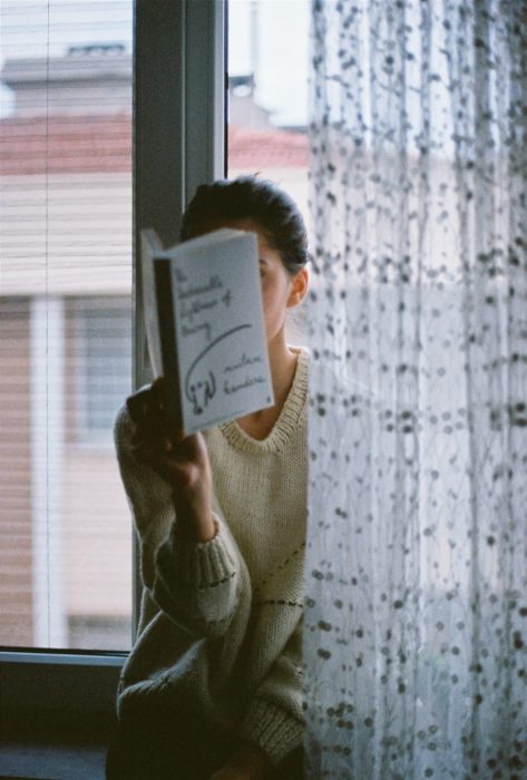 Mujer leyendo en la ventana de su casa