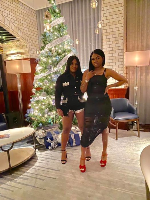 Ashley Thomas y Toya Wimberlyposando frente a un pino de Navidad 