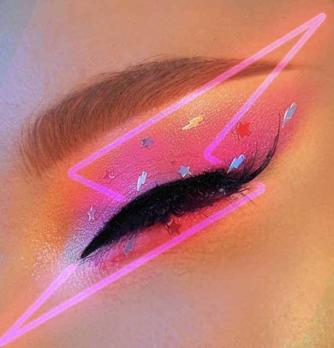 Sombra para ojos en tono durazno con decorado de estrellas y delineado en efecto rosa neón