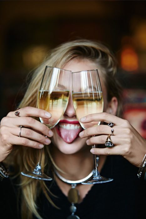 Chica con dos copas de champagne frente al rostro