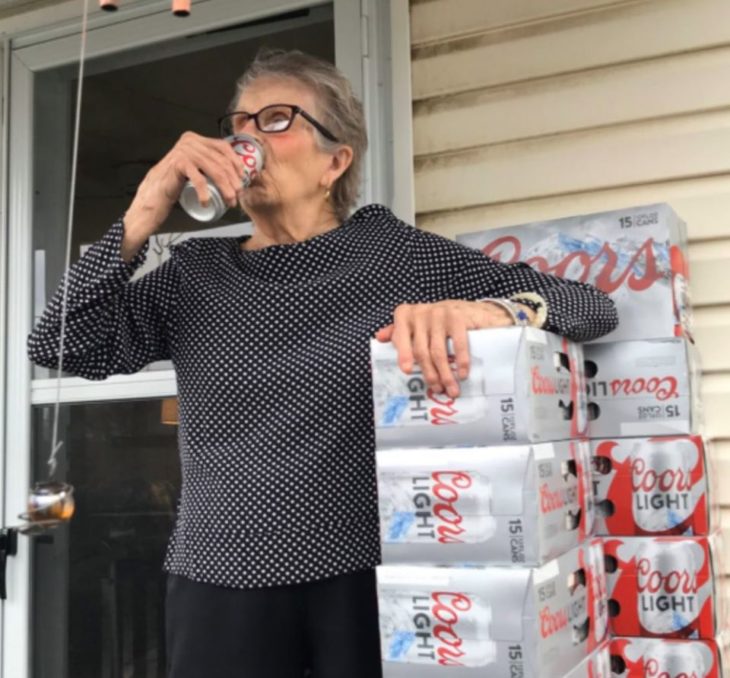 Abuelita recargada en paquetes de cerveza cerrados