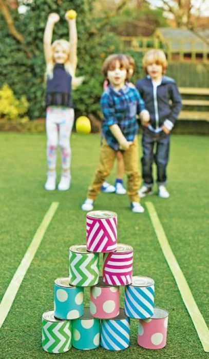 Niños jugando boliches con latas de colores