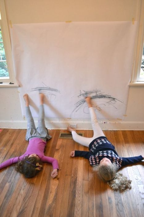 Niños dibujando con los pies sobre la pared