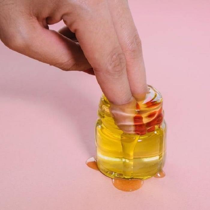 Mujer introduciendo dedos en frasquito de aceite de oliva