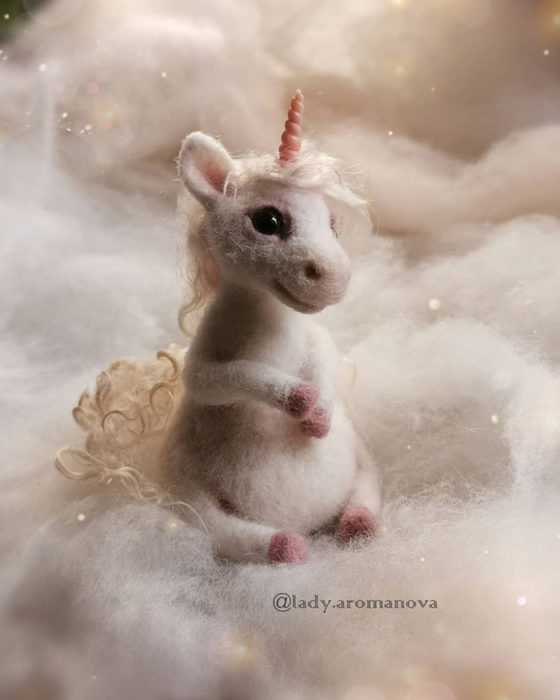 Figura de fieltro creada por la artista rusa Anna Romanova unicornio sentado sobre fieltro blanco 