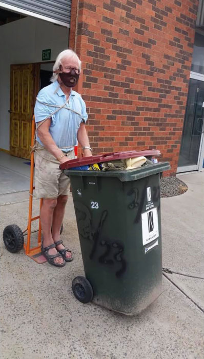 Señor disfrazado de hanibal lecter mientras saca la basura de su casa 