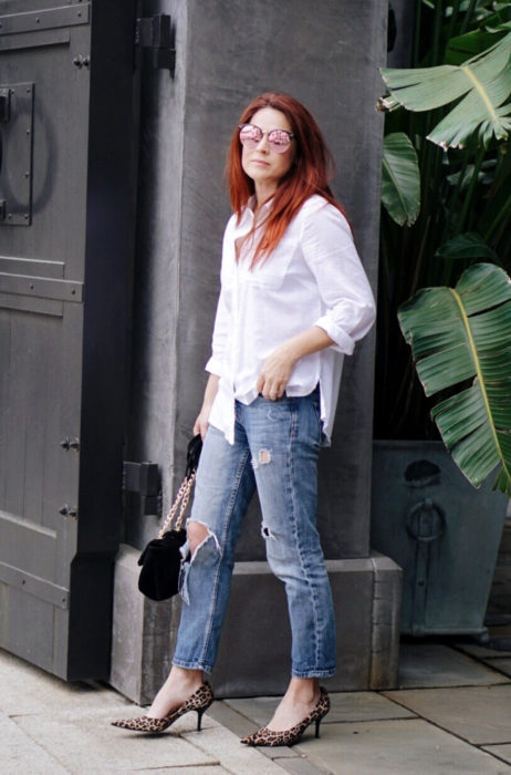 Atuendos con tu boyfriend shirt, camisa de tu novio, blusa oversized blanca, jeans desgastados, tacones animal print, mujer pelirroja con lentes tornasol