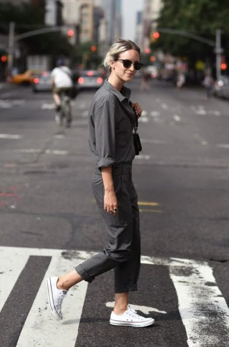 Atuendos con tu boyfriend shirt, camisa de tu novio, blusa oversized gris, mujer cruzando la calle con lentes y pantalón de trabajo, oficina, tenis blancos converse