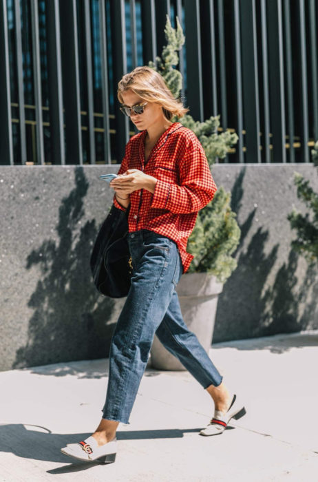 Atuendos con tu boyfriend shirt, camisa de tu novio, blusa oversized roja, con mom jeans, flats con tacones, mujer mirando su celular mientras camina