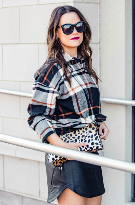 Atuendos con tu boyfriend shirt, camisa de tu novio, blusa oversized a cuadros, negros, blancos y anaranjados, minifalda de vinipiel, lentes de sol oscuros, bolsa de mano animal print, mujer de cabello castaño ondulado