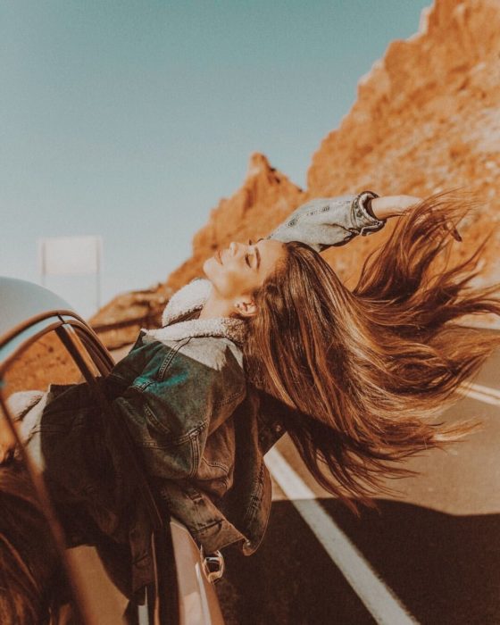 Chica en viaje en carretera asomandose por la ventana