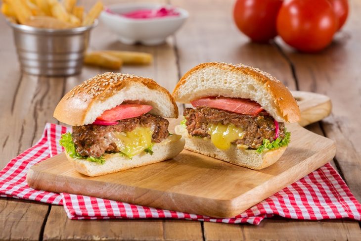 Hamburguesa rellena de queso amarillo con lechuga y tomate