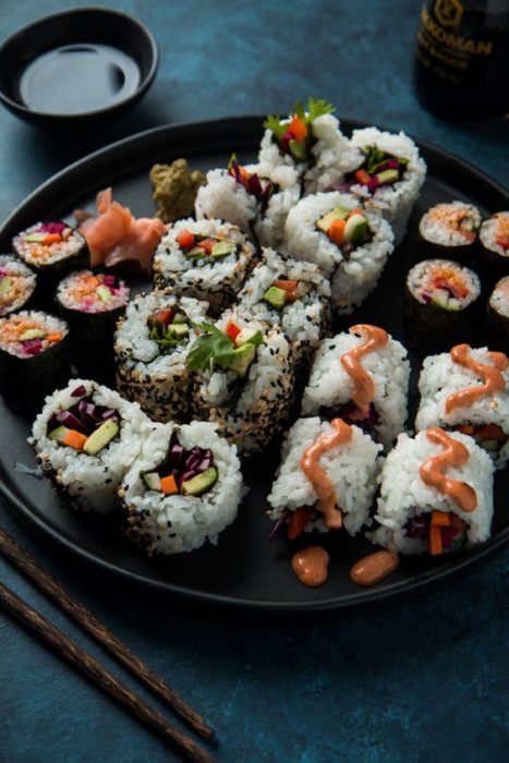 Suchi de pescado con aguacate en un plato negro amplio