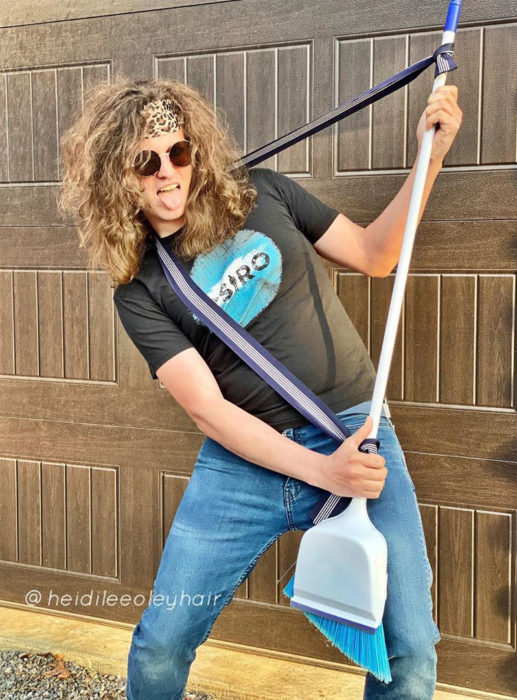 Chico con el cabello despeinado con una banda en la frente y sosteniendo una escoba para rockear 