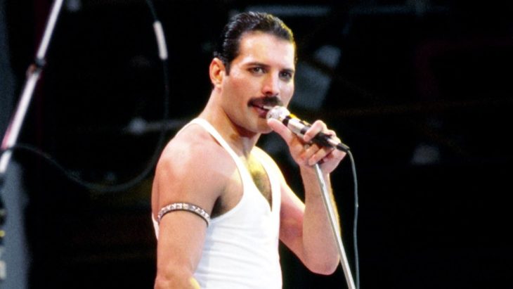 Freddie Mercury sosteniendo un micrófono mientras canta 